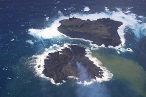 写真1. 新島成長の様子．12月初旬以降，南西から北西側に大きく拡大し，西之島に接近している．南東から撮影．