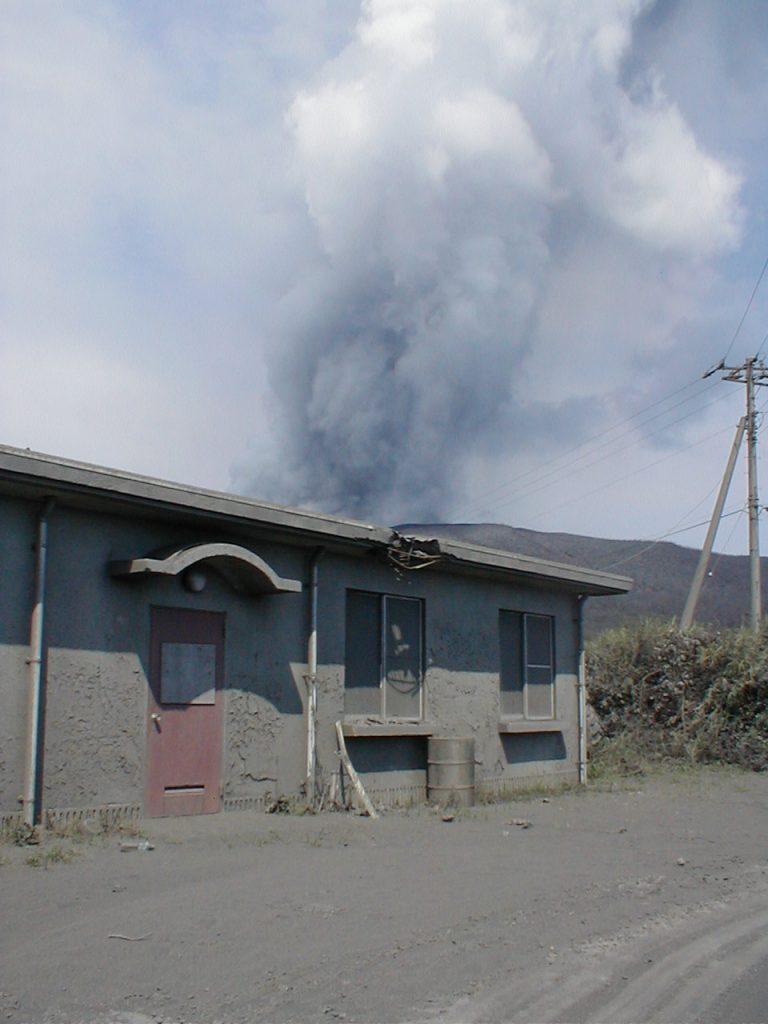 三宅島雄山の中腹の村営牧場から見た噴煙と 噴石で壊れた施設の屋根（2000年８月）